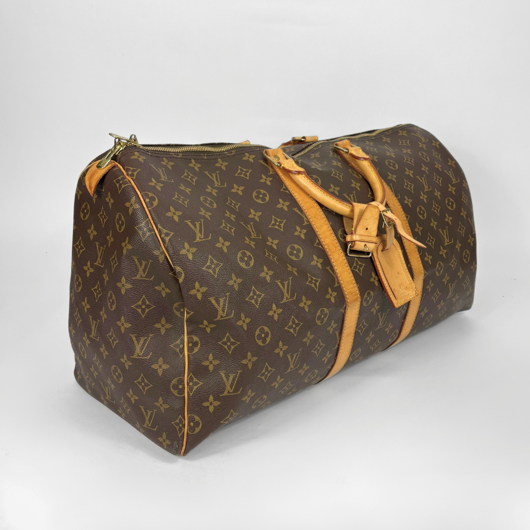 Brown travel bag with yellow monogram pattern on a white background