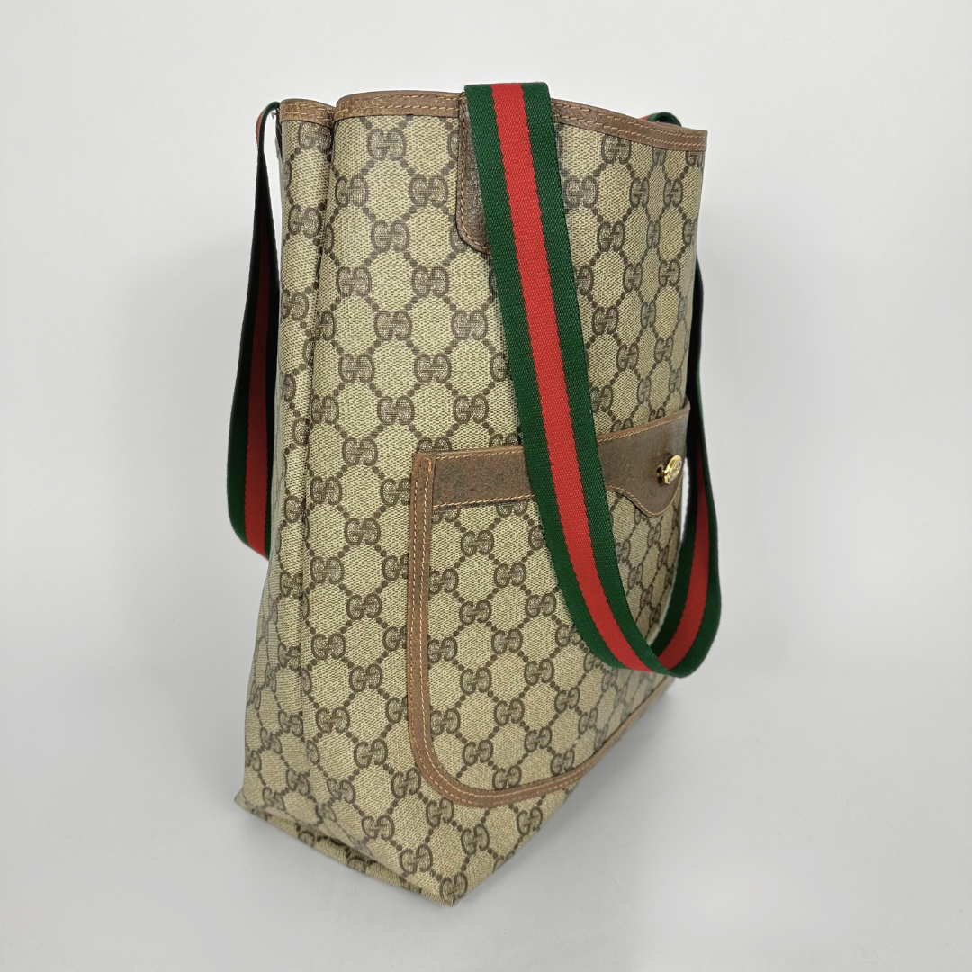 Designer tote bag with monogram pattern and red and green stripes on a light gray background