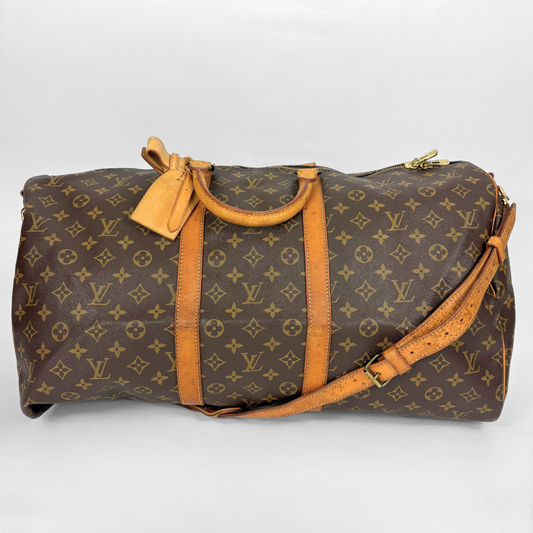 Brown duffel bag with tan leather straps and handle on a white background