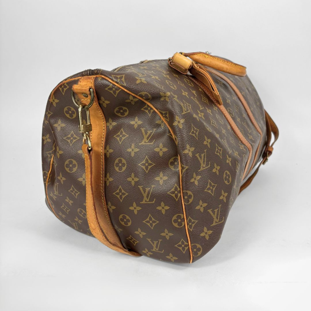 Brown duffel bag with tan leather straps and handle on a white background