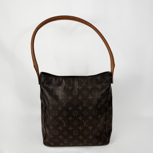 A Louis Vuitton Axelväska i kanvas med monogrammönster och brunt läderhandtag, fotograferad mot en vit bakgrund.