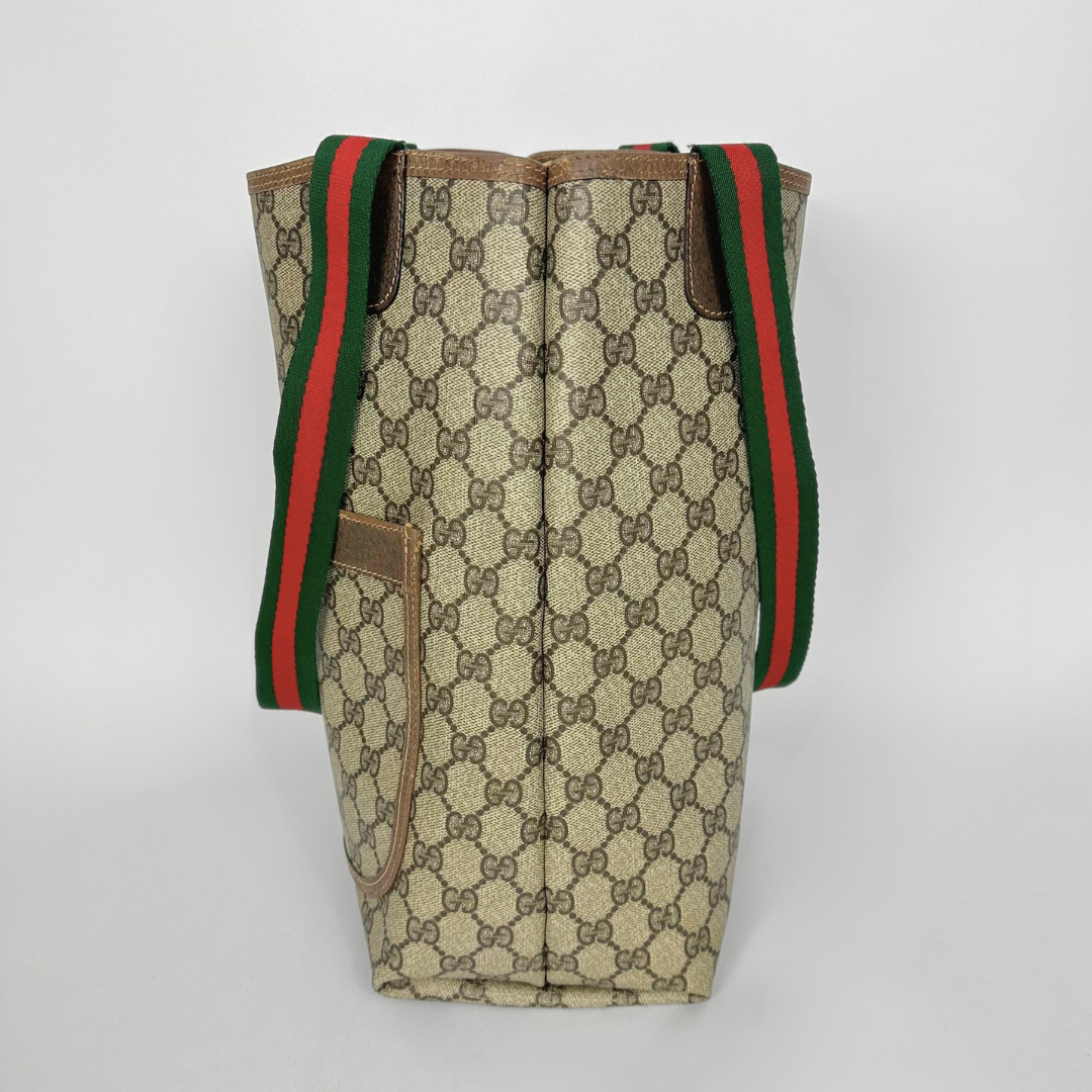 Designer tote bag with monogram pattern and red and green stripes on a light gray background