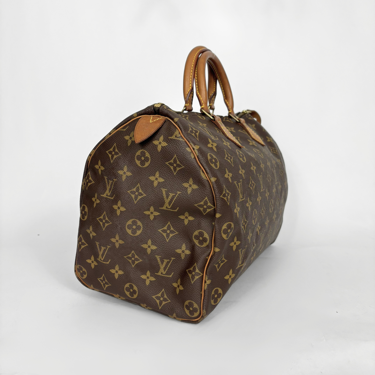 Bolso marrón con estampado de monograma sobre fondo blanco.