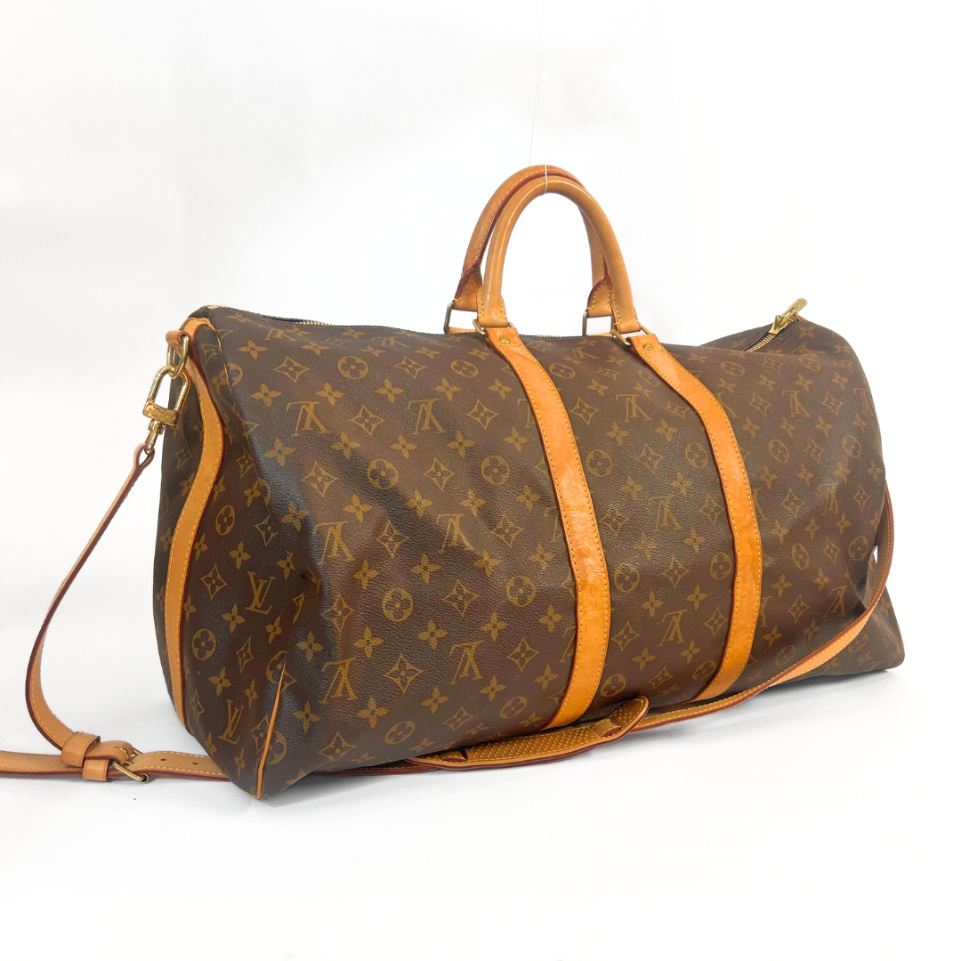Braune Reisetasche mit orangefarbenen Riemen auf weißem Hintergrund