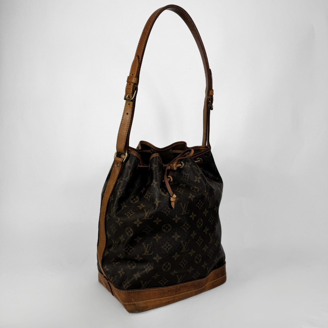A Louis Vuitton Monogram Bucket bag in dark brown coated canvas with tan leather trim and a matching shoulder strap, shown against a light gray background.