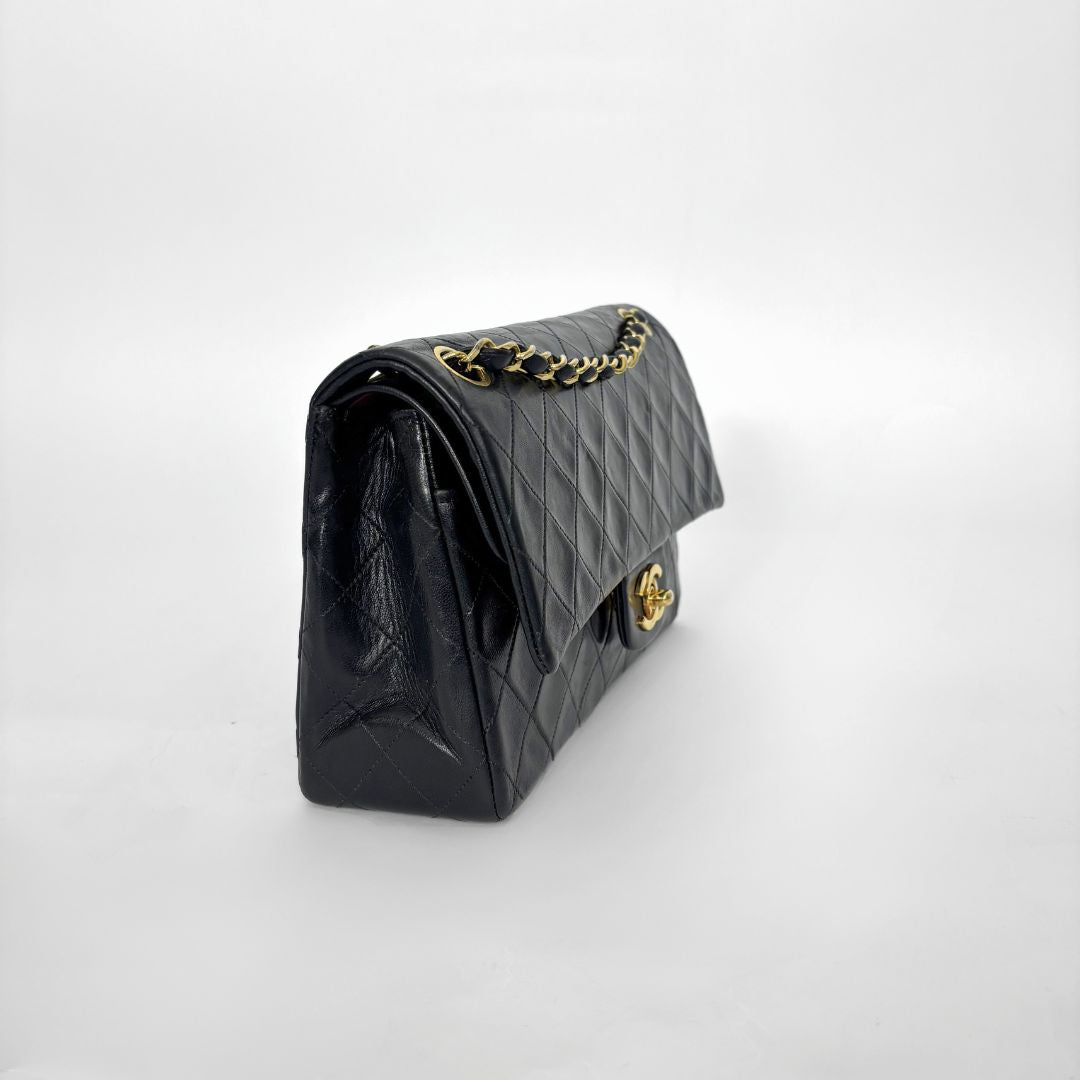 Black quilted handbag with gold hardware on a white background