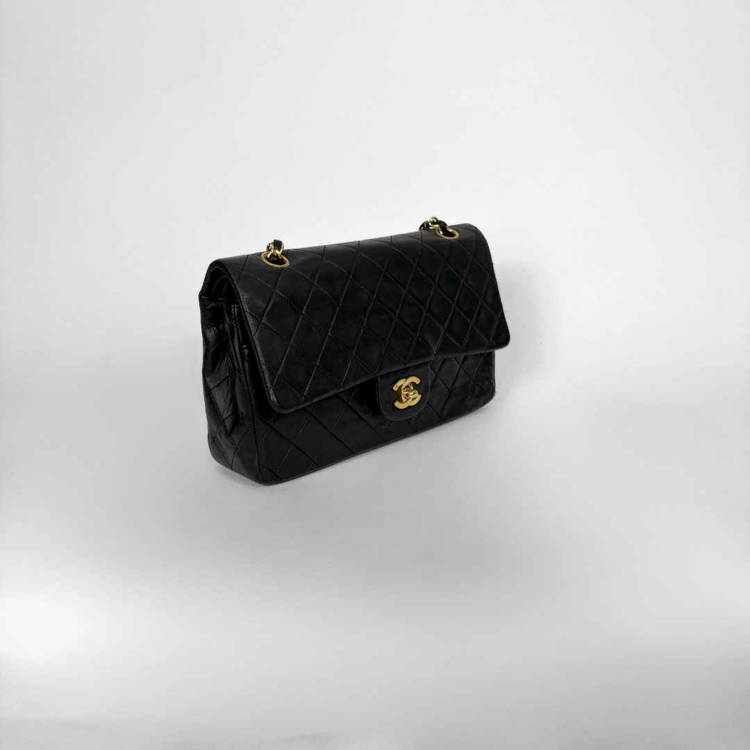 Black quilted Chanel shoulder bag with gold hardware on a white background