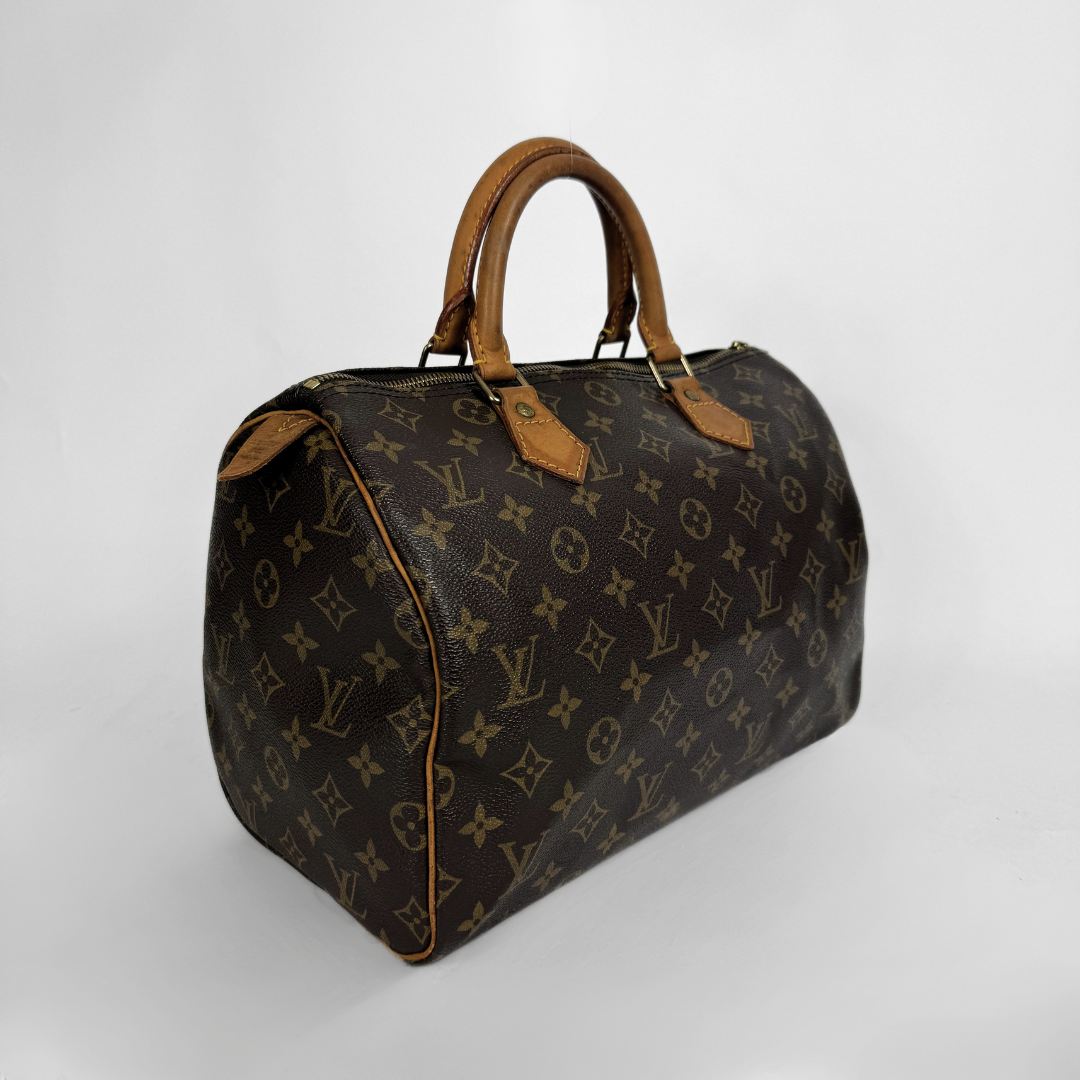 A Louis Vuitton monogram canvas duffel bag with tan leather handles and trim, photographed on a light gray studio background.