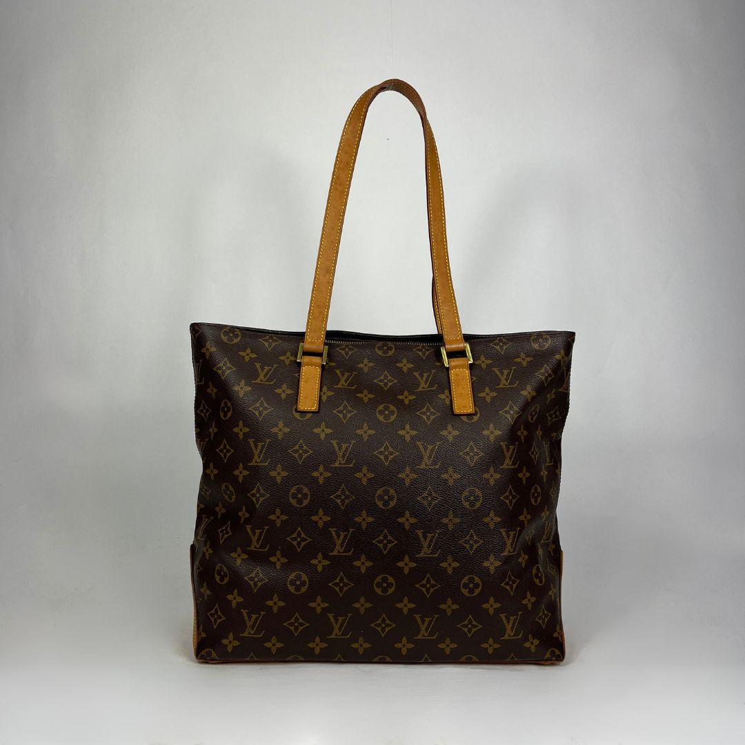 A Louis Vuitton monogram canvas tote bag with tan leather shoulder straps, photographed against a neutral gray studio background.