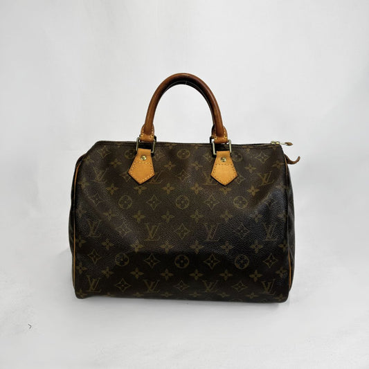 A Louis Vuitton monogram Speedy handbag in dark brown coated canvas with tan leather handles and trim, photographed against a plain white background.