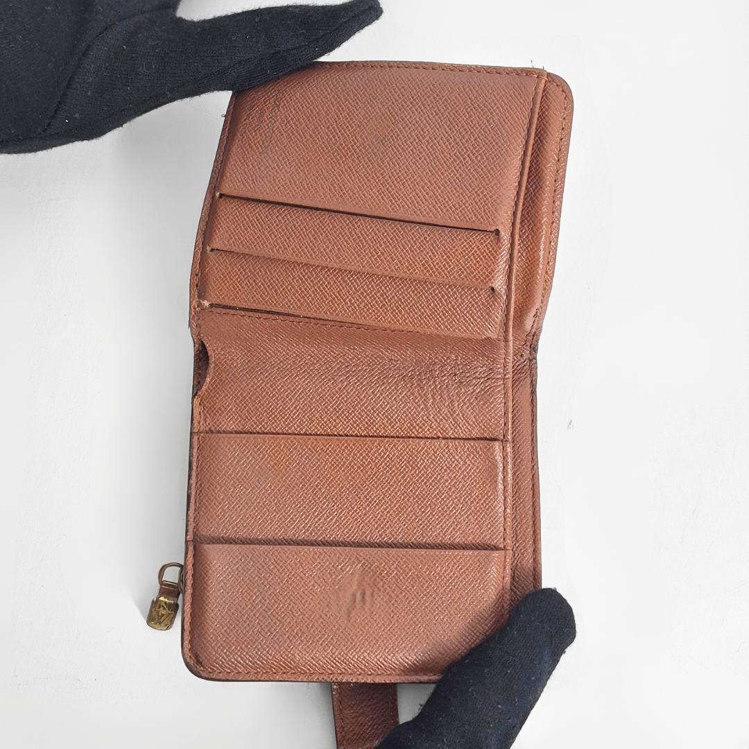 Brown leather wallet held by a gloved hand on a white background