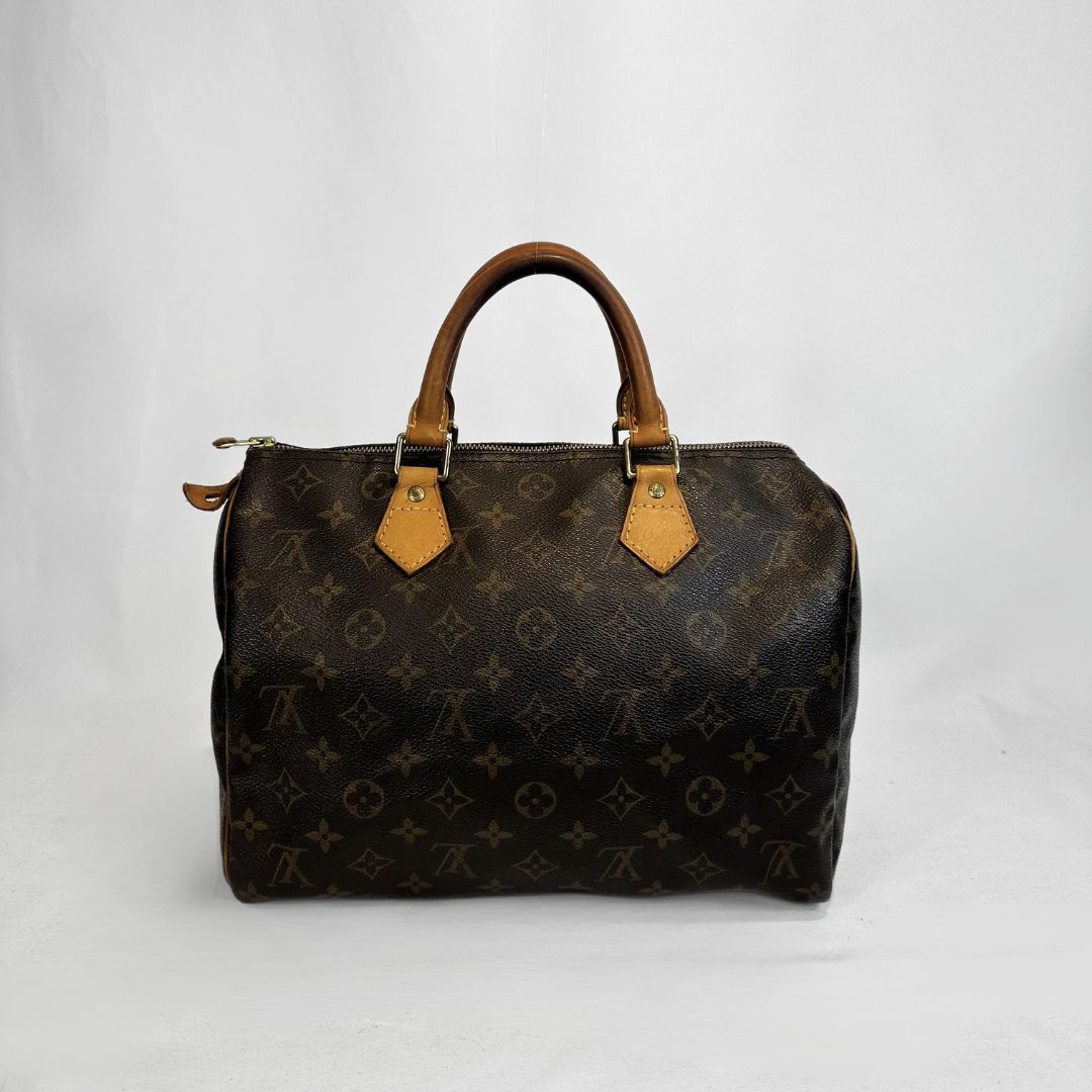 A Louis Vuitton monogram Speedy handbag in dark brown coated canvas with tan leather handles and trim, shown against a plain light gray background.
