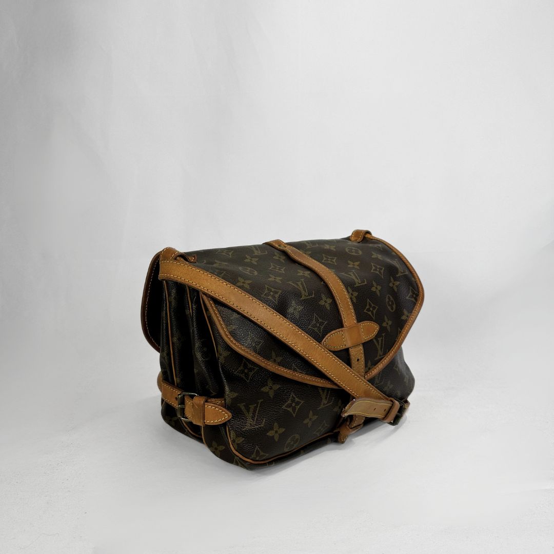 A vintage Louis Vuitton monogram shoulder bag in dark brown coated canvas with tan leather trim and straps, photographed on a light gray studio background.