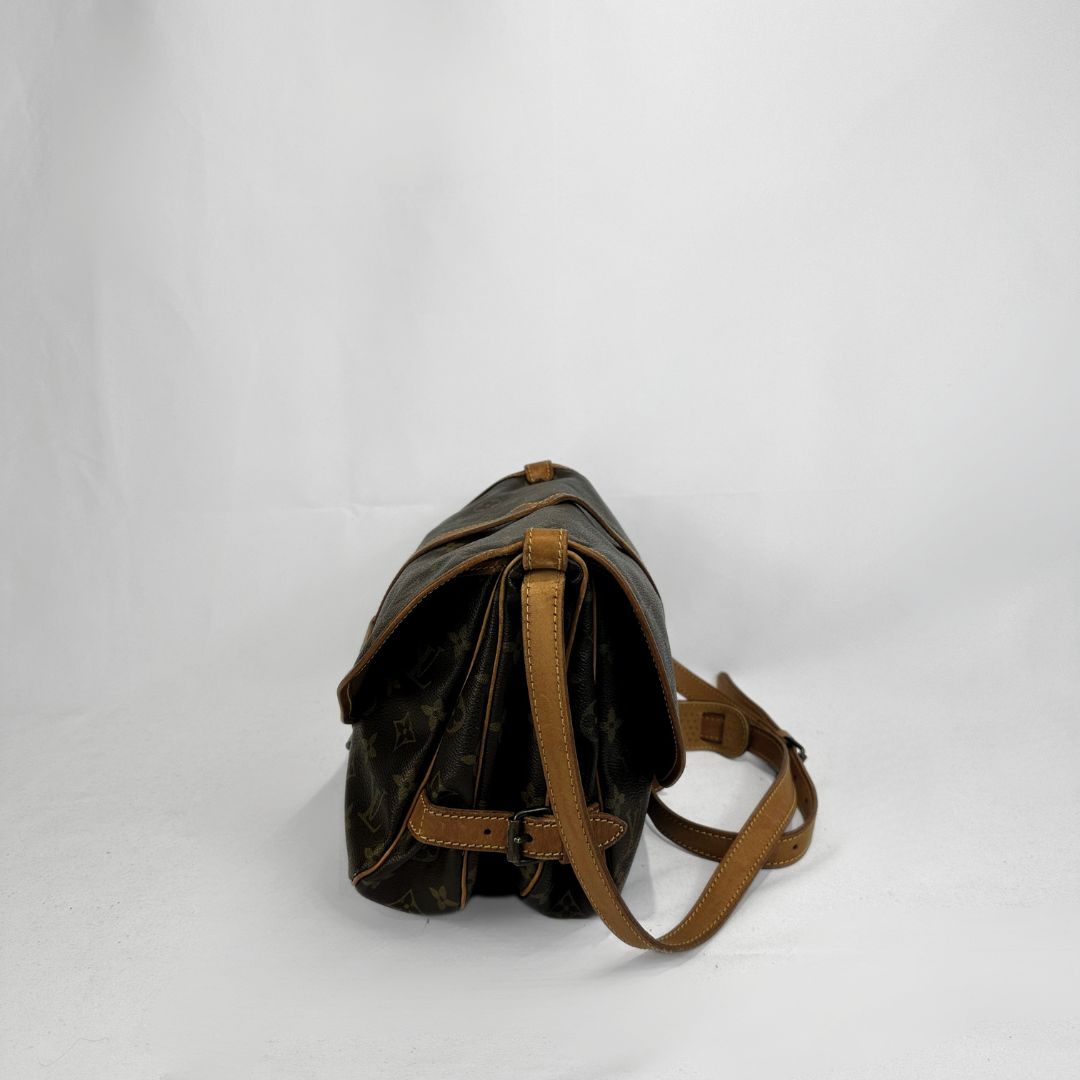 Louis Vuitton monogram canvas shoulder bag with tan leather trim and strap, shown from a side profile view on a white studio background.