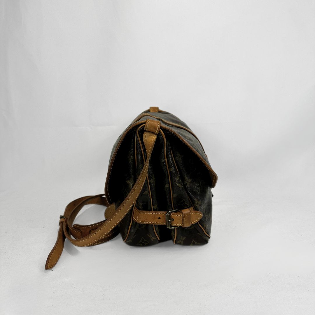 A vintage Louis Vuitton shoulder bag in brown monogram canvas with tan leather trim and strap, photographed from the side against a white studio background.
