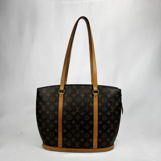 Louis Vuitton monogram canvas tote bag with tan leather shoulder straps and trim, shown against a white studio background.