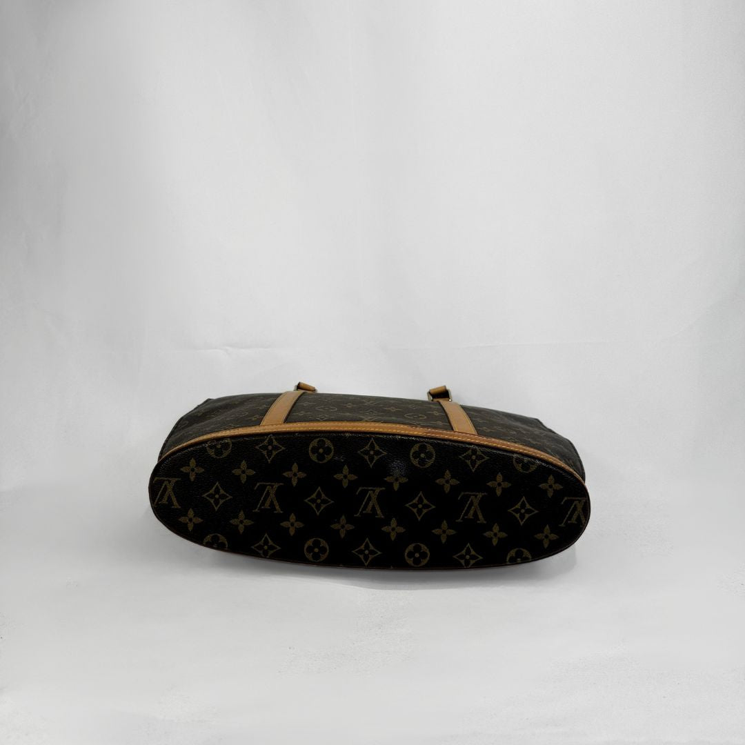 A Louis Vuitton monogram canvas duffel bag in dark brown and tan, photographed against a plain white studio background.