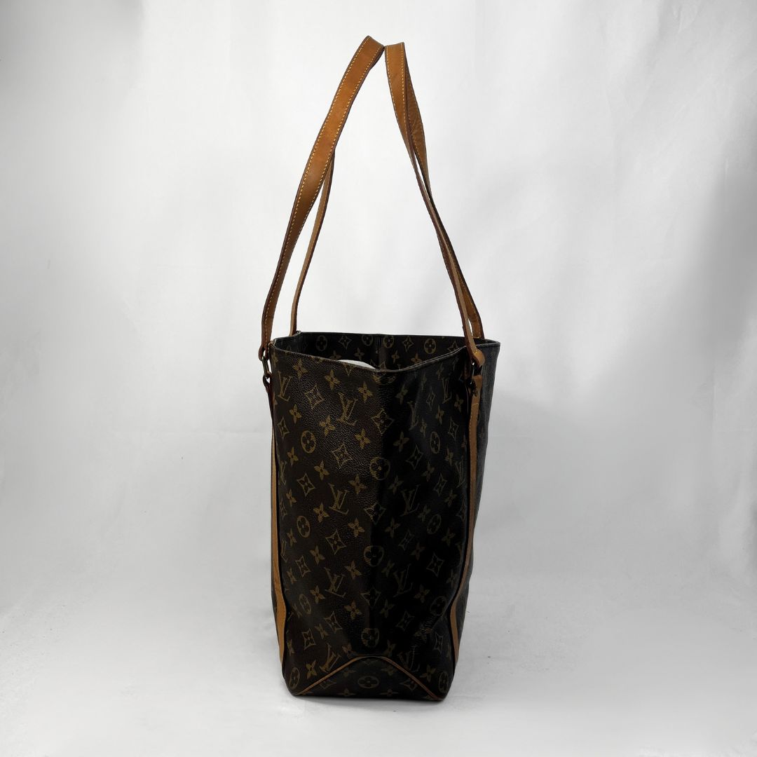 A vintage Louis Vuitton monogram tote bag in dark brown coated canvas with tan leather shoulder straps, shown against a white studio backdrop.