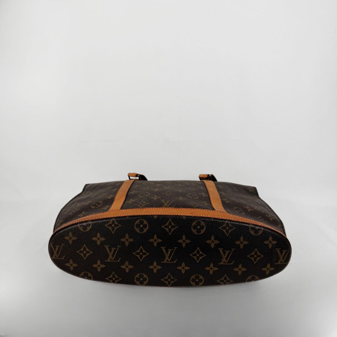 Louis Vuitton monogram canvas shoulder bag in brown with tan leather trim and handles, shown against a plain light gray background.