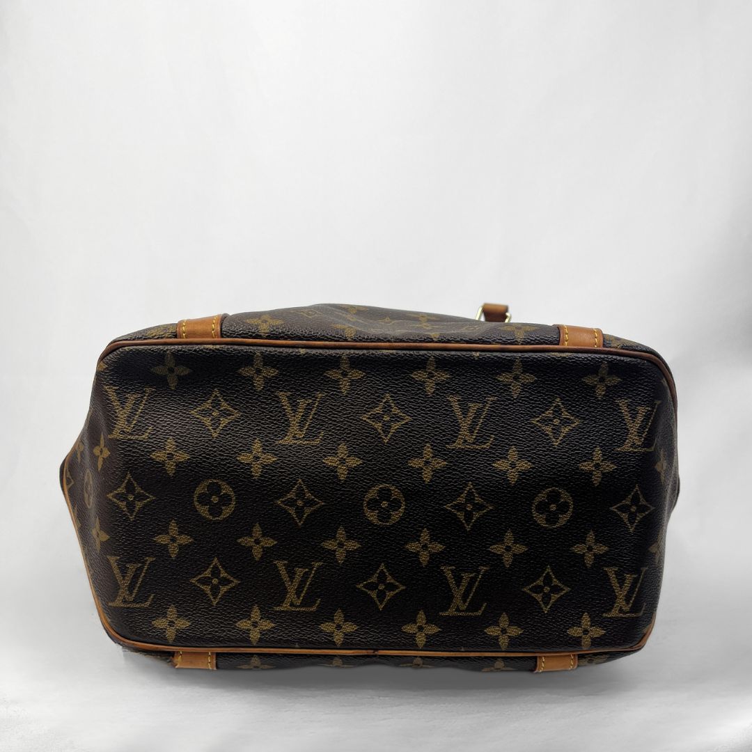 Louis Vuitton monogram canvas duffel bag shown from the bottom front view, featuring the classic dark brown and tan monogram pattern with tan leather trim on a light gray background.