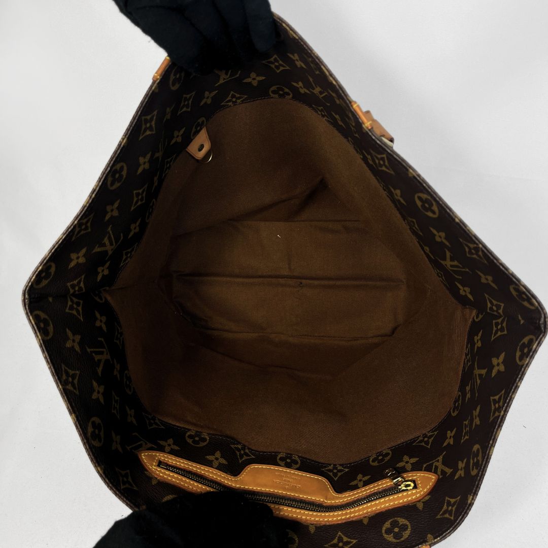 Open Louis Vuitton monogram canvas tote bag showing the brown interior lining and zipper closure, photographed against a plain light background.