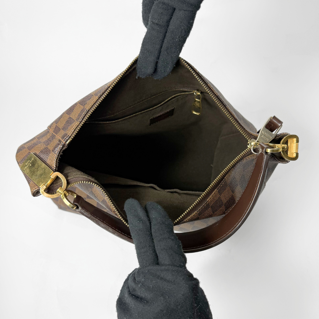 Braune karierte Handtasche mit goldenem Verschluss auf weißem Hintergrund