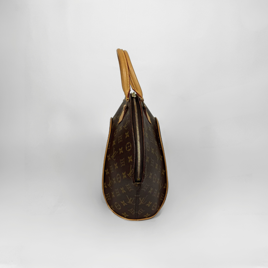 Brown handbag with gold accents held by a gloved hand on a white background