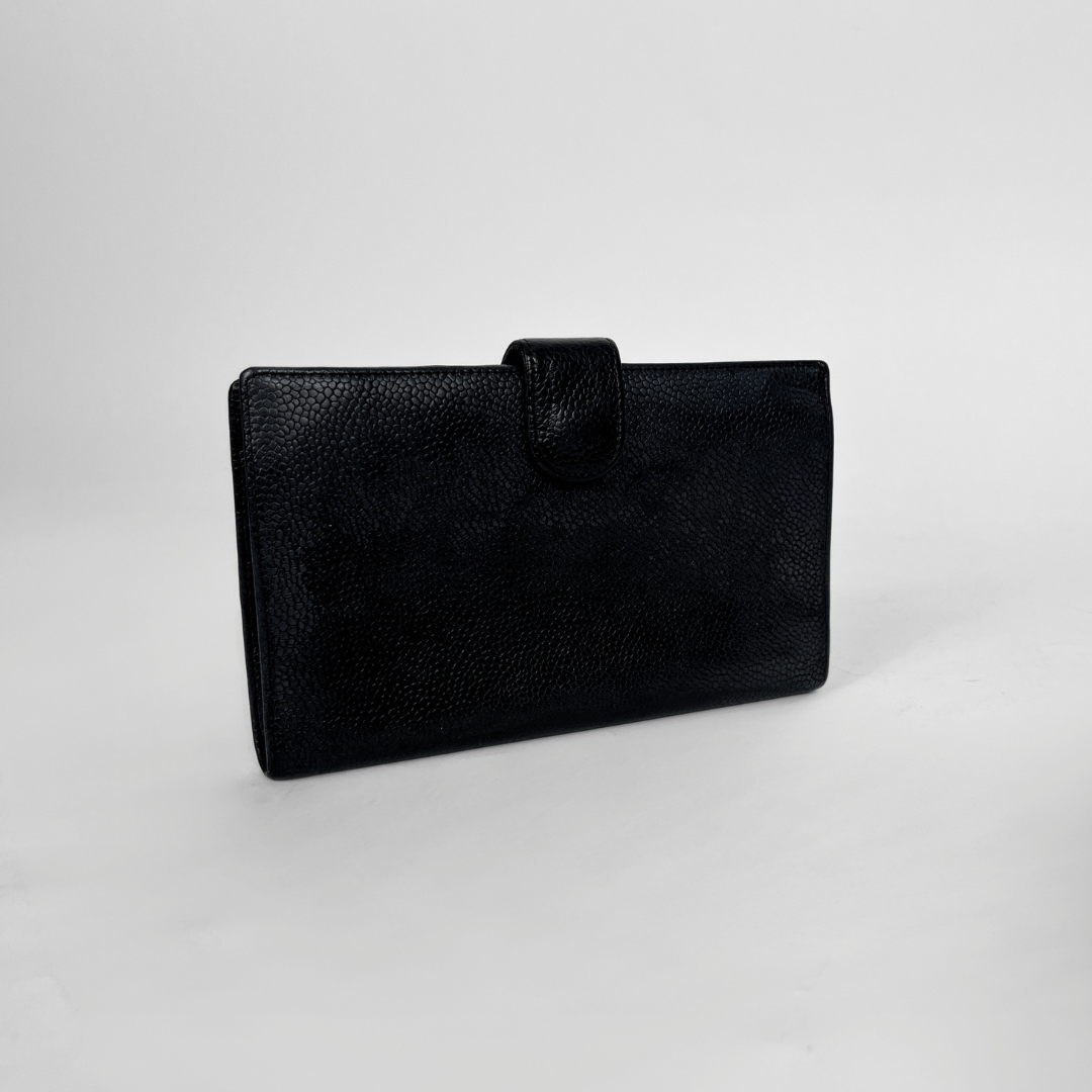 A black textured leather clutch wallet with a top strap closure, photographed on a neutral light gray background.