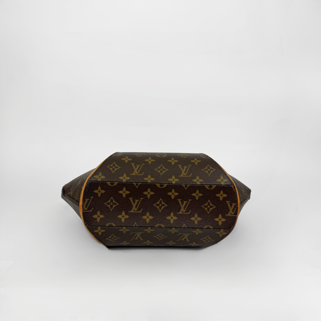 Brown handbag with gold accents held by a gloved hand on a white background