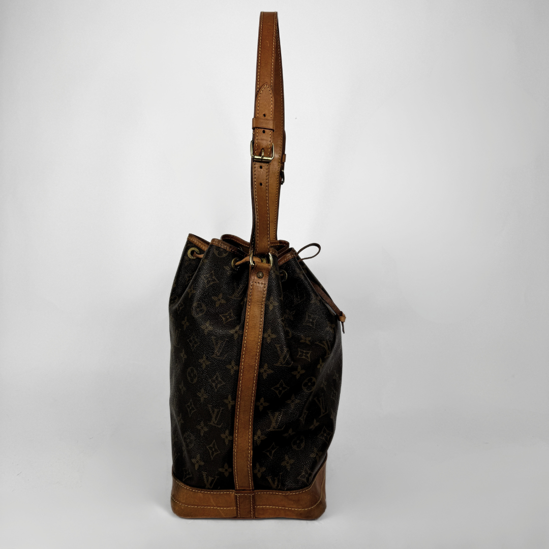Louis Vuitton monogram canvas bucket bag with brown leather trim and shoulder strap, shown against a light gray background.
