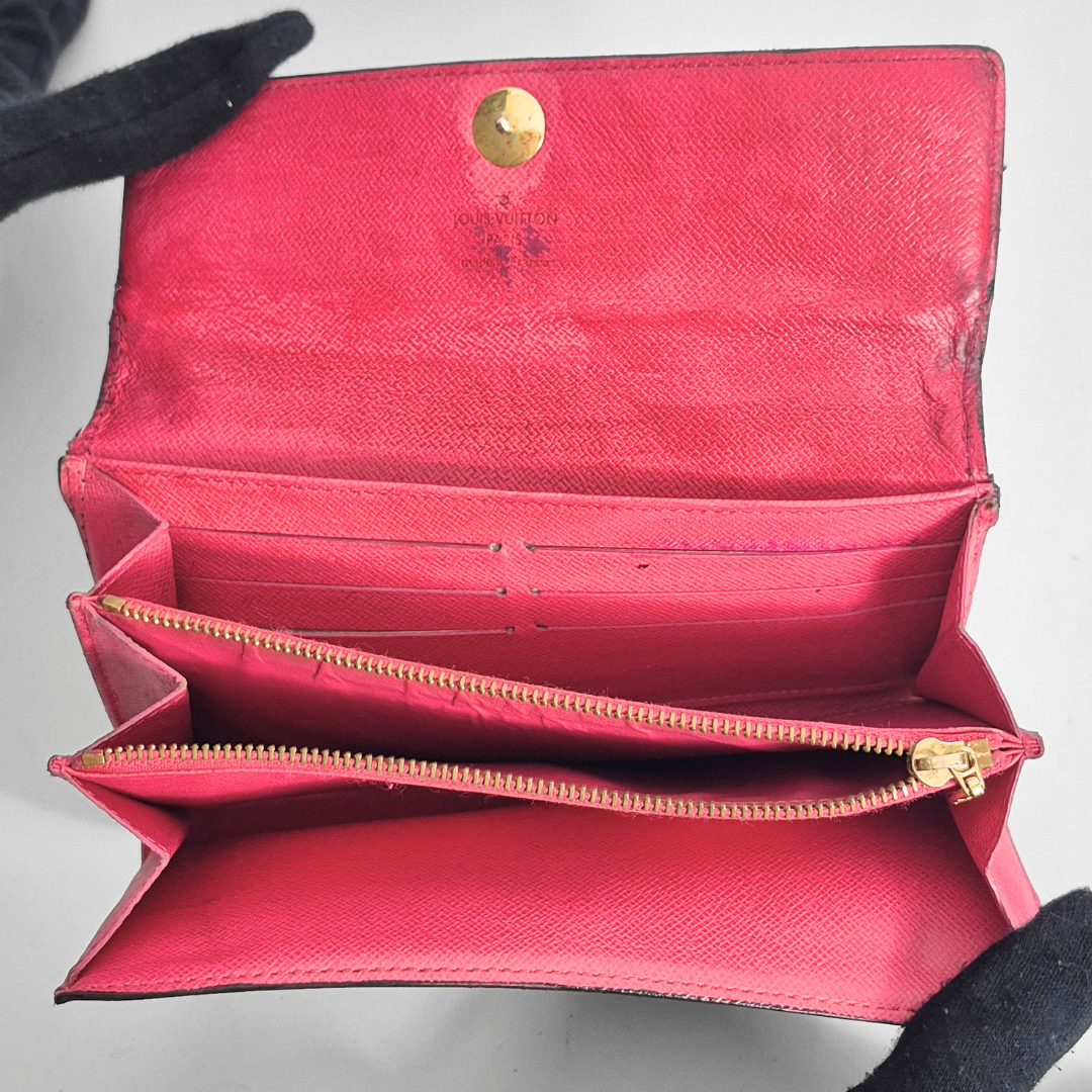 Cartera roja abierta con detalles dorados sobre fondo gris