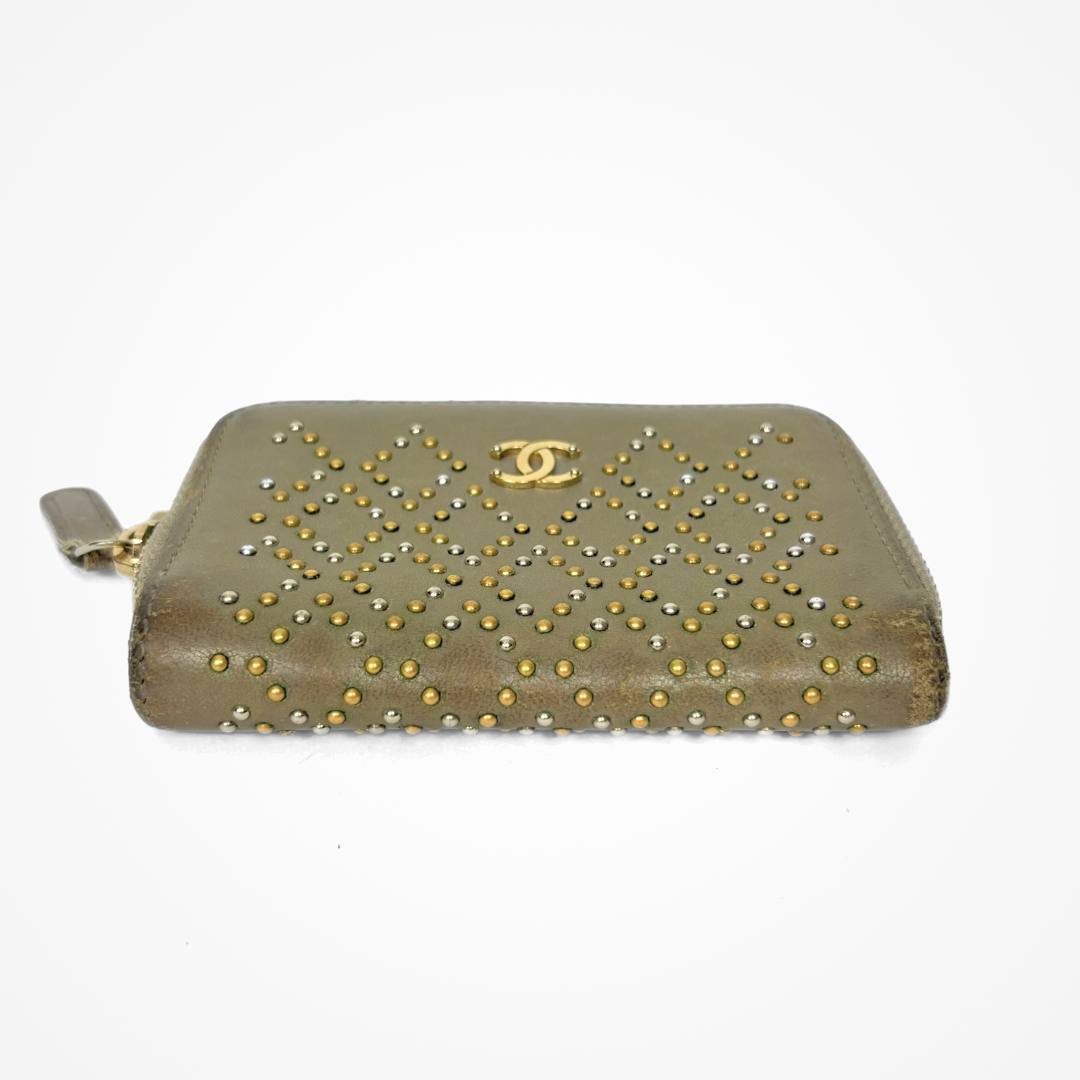 Beige Chanel wallet with gold studs on a white background