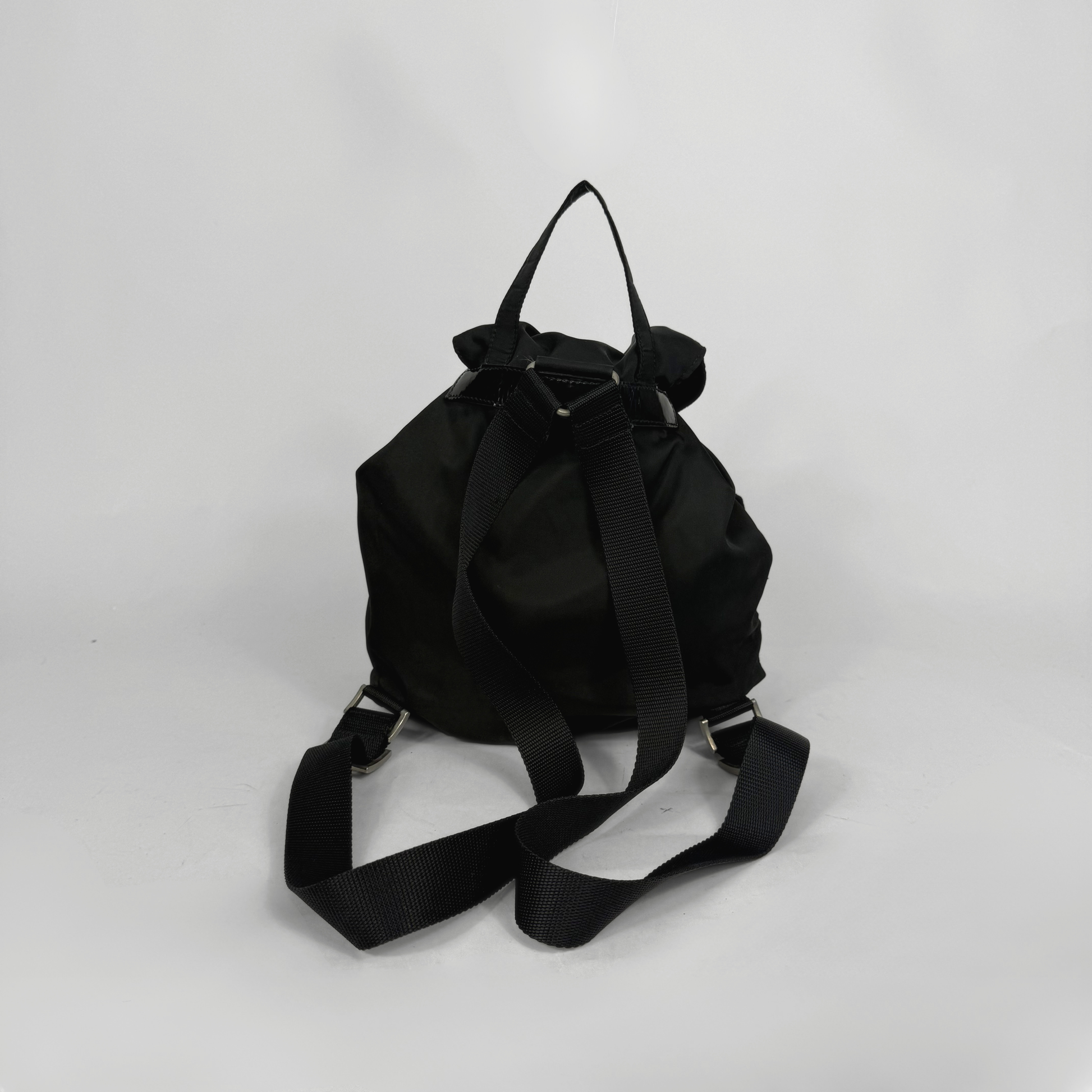 Black backpack and black ballet flats on a light gray background