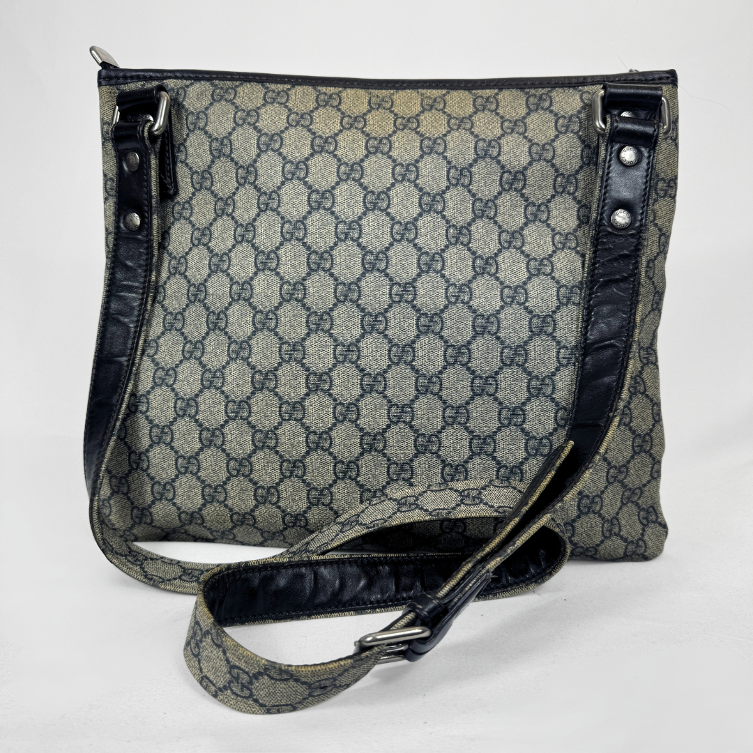 Gucci GG Supreme Web Flat Messenger bag in signature monogram canvas with green and red Web detailing and leather trims, displayed on a light grey background.