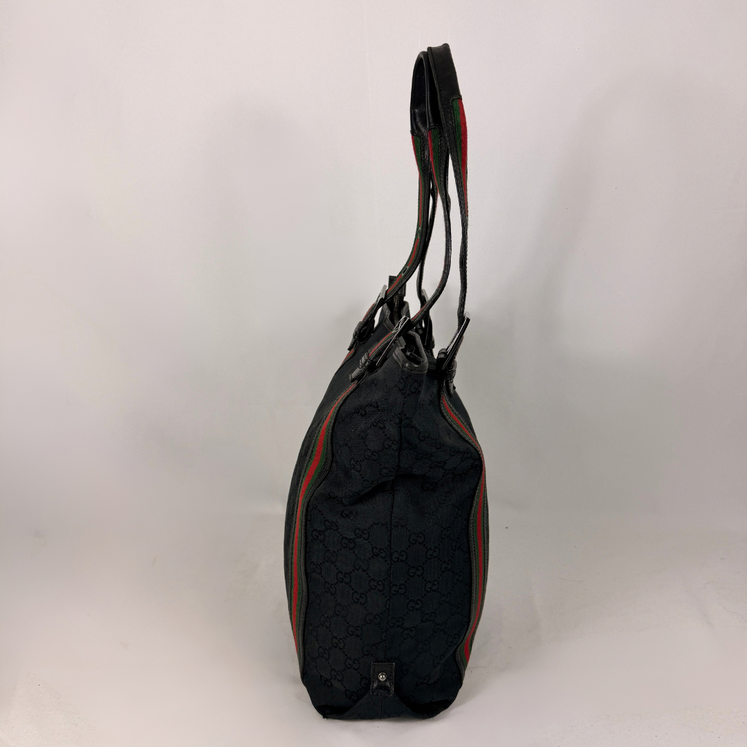 A black Gucci shoulder bag with the brand's signature GG monogram pattern and green and red web stripe details, shown from a side profile view against a plain white background.