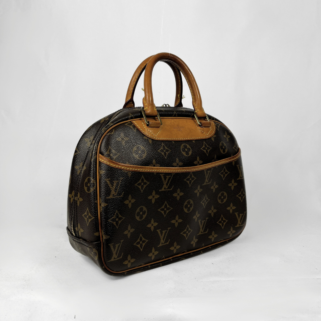 A vintage Louis Vuitton Alma BB handbag in brown monogram canvas with tan leather trim and handles, photographed on a white studio background.