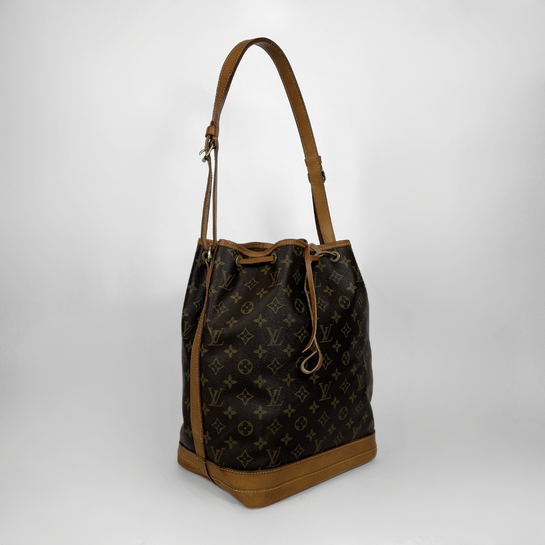 Louis Vuitton monogram canvas bucket bag with brown leather trim and shoulder strap, shown on a light gray background.