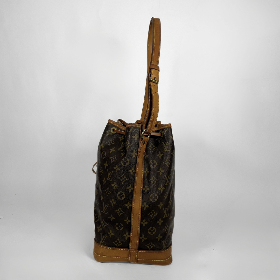 Louis Vuitton monogram canvas bucket bag with tan leather trim and shoulder strap, shown against a plain light gray background.