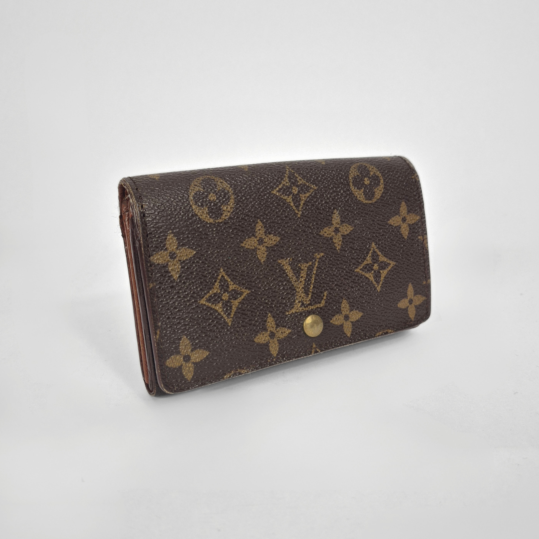 Brown wallet with gold monogram pattern on a light gray background