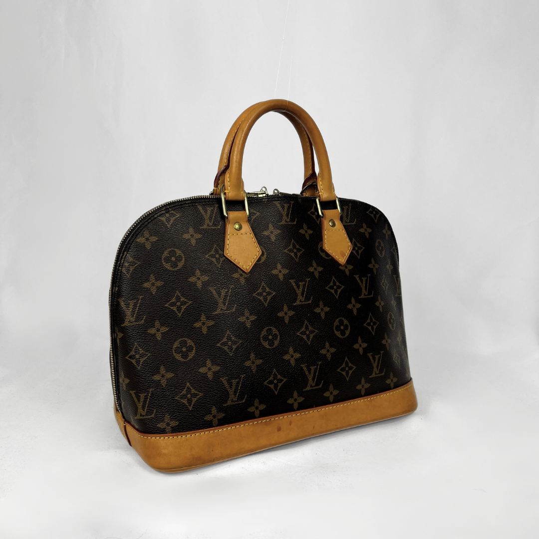 Louis Vuitton monogram canvas dome handbag with tan leather handles and trim, photographed on a light gray studio background.