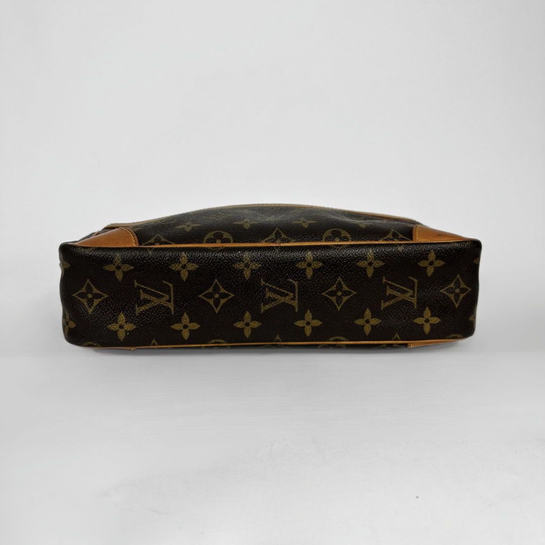 A Louis Vuitton monogram canvas toiletry bag shown from the side, featuring dark brown coated canvas with tan leather trim and a gold-tone zipper.