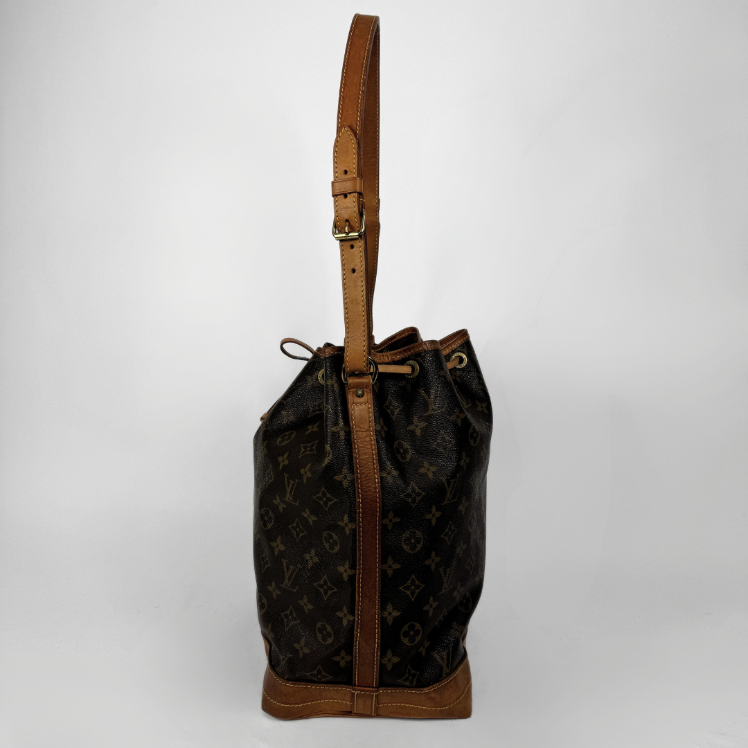 A Louis Vuitton monogram canvas bucket bag with brown leather trim and a single shoulder strap, photographed against a neutral light gray background.