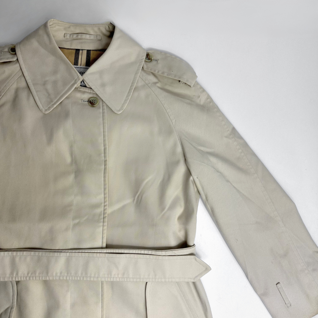 Beige trench coat on a mannequin against a gray background