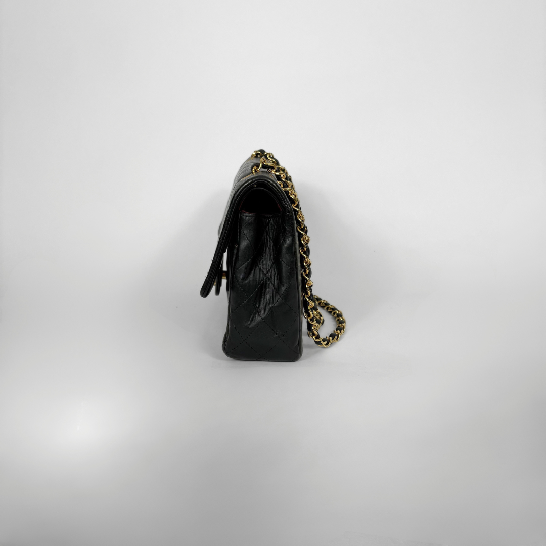 Black quilted Chanel shoulder bag with gold hardware on a white background