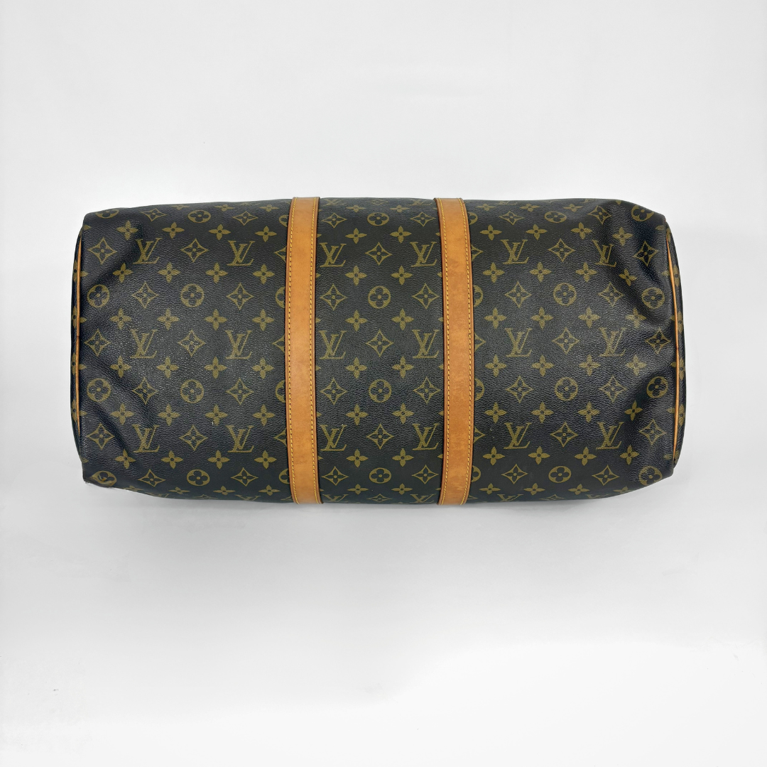 Louis Vuitton monogram travel bag with brown leather straps on a white background