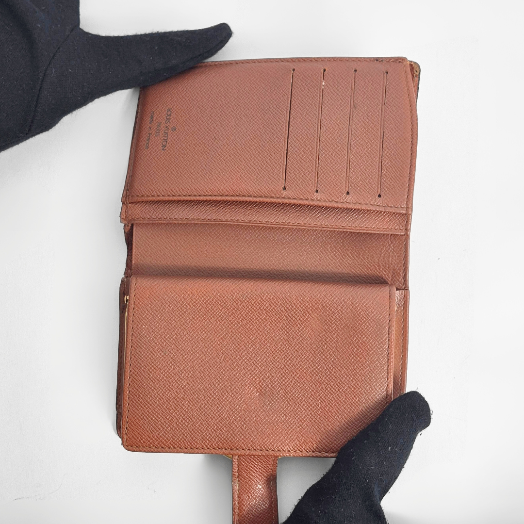 Braune, strukturierte Geldbörse, gehalten von einer behandschuhten Hand vor weißem Hintergrund