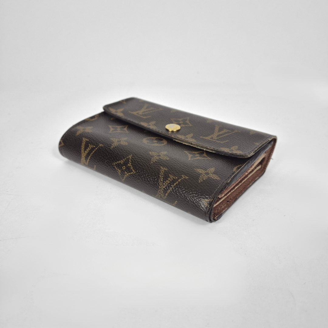 Louis Vuitton wallet with monogram pattern on a light gray background