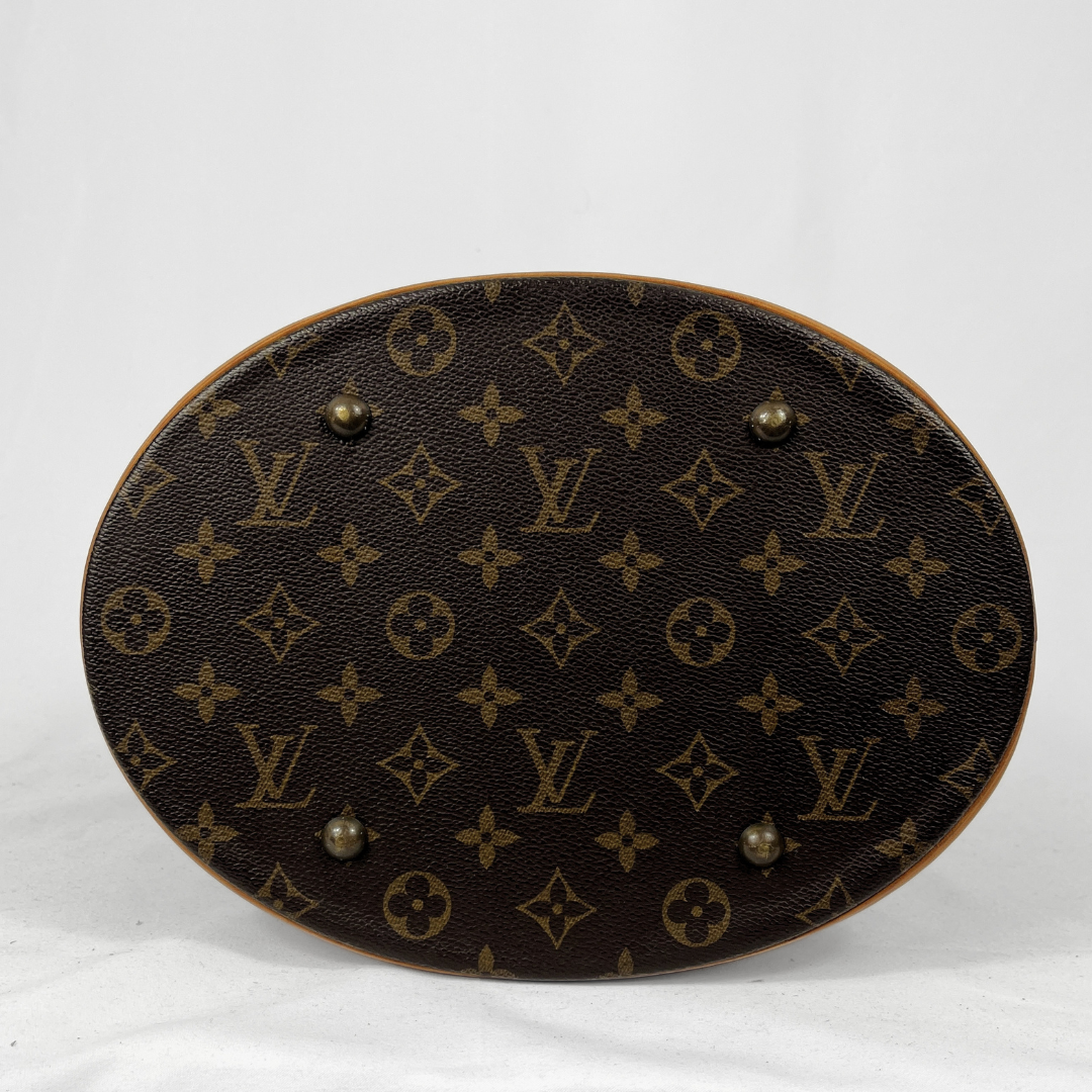 An oval-shaped Louis Vuitton monogram canvas bag bottom or tray, featuring the classic dark brown and tan monogram pattern with four metal studs on a white fabric background.