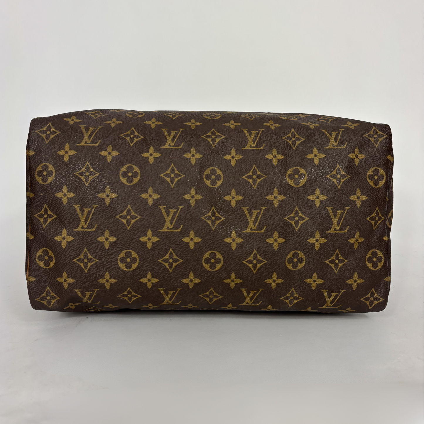 Bolso de piel marrón con estampado de monograma dorado sobre fondo blanco.