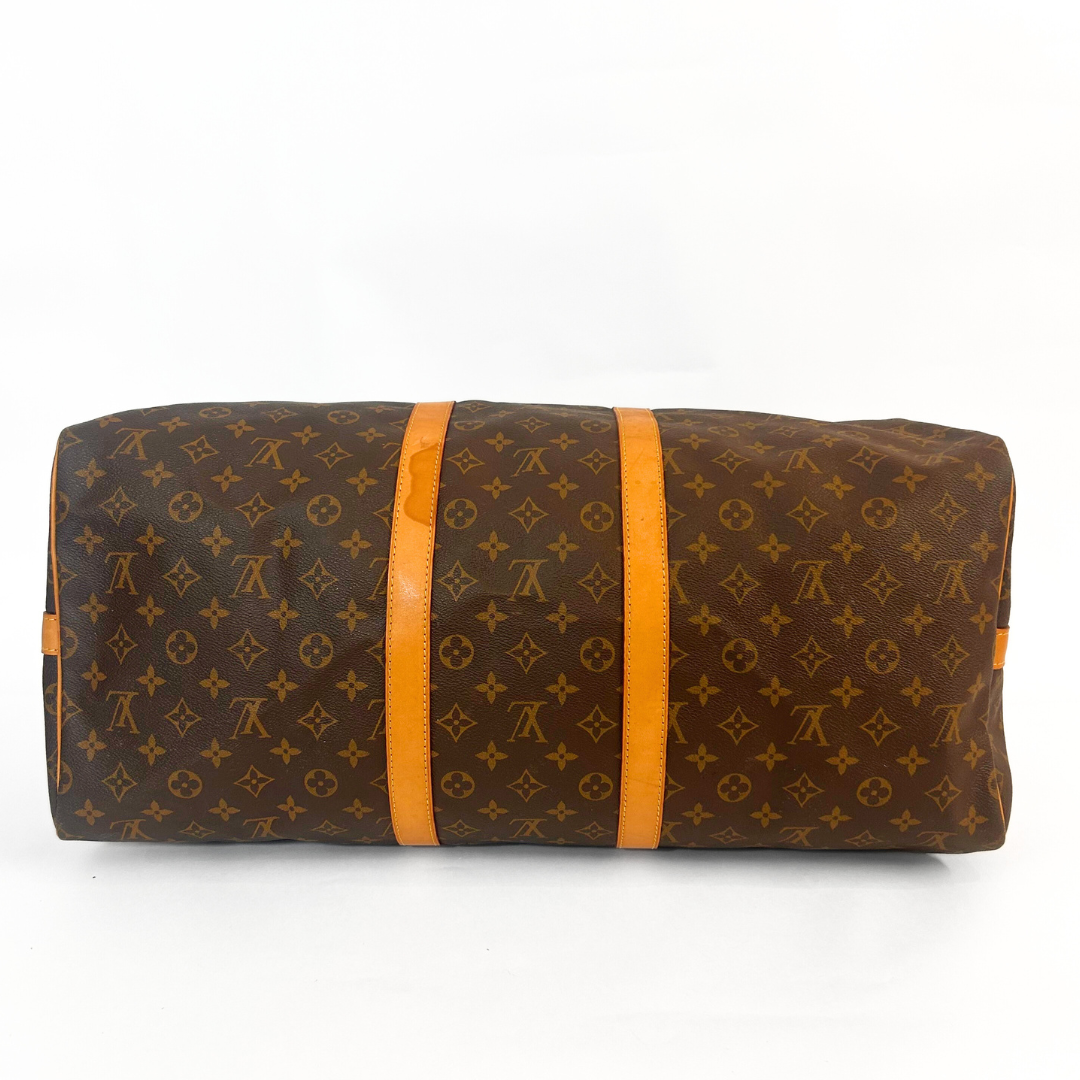 Braune Reisetasche mit orangefarbenen Riemen auf weißem Hintergrund